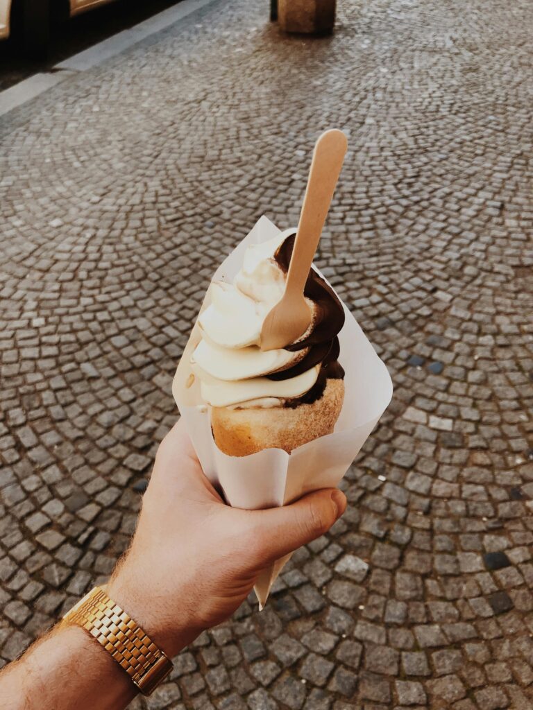 Indulge in a creamy ice cream cone with chocolate topping on a cobblestone street in Prague.