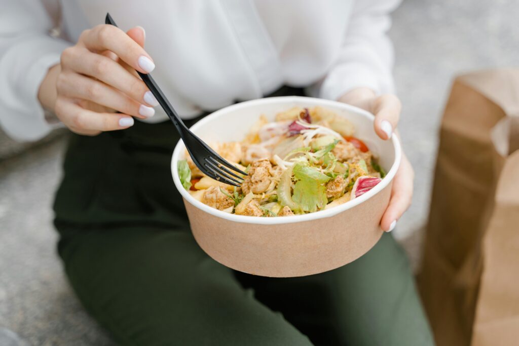 Close-up of a woman eating a fresh salad outdoors, exuding healthy and casual vibes.